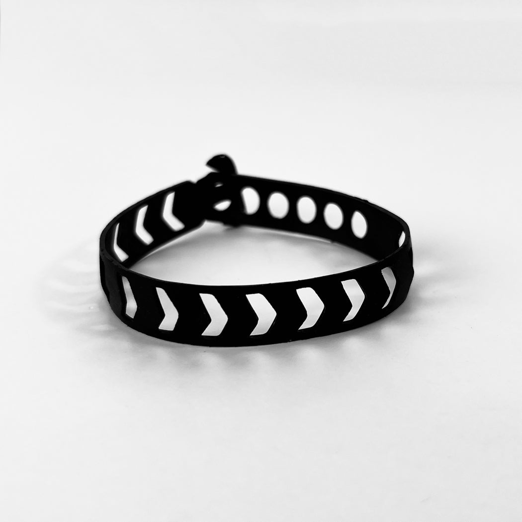 This bracelet was made by cutting intricate arrow or chevron shaped designs into a bicycle inner tube in a repeat pattern. The bracelet is .5 inches wide. It has a t-shape clasp that fits into one of six holes making this bracelet suitable for a wide range of wrist sizes.