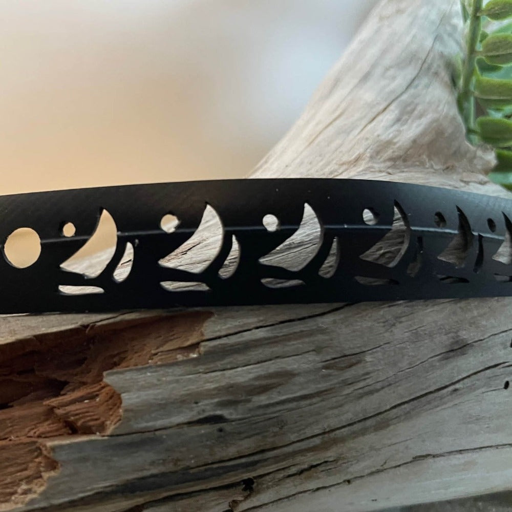 This bracelet was made by cutting sailboat shaped designs into a bicycle inner tube in a repeat pattern. The bracelet is .5 inches wide. It has a t-shape clasp that fits into one of six holes making this bracelet suitable for a wide range of wrist sizes.