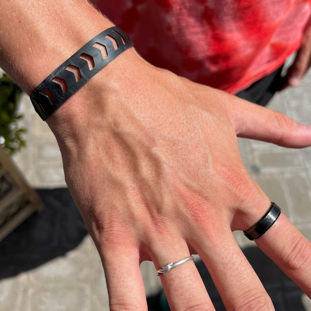 This bracelet was made by cutting intricate arrow or chevron shaped designs into a bicycle inner tube in a repeat pattern. The bracelet is .5 inches wide. It has a t-shape clasp that fits into one of six holes making this bracelet suitable for a wide range of wrist sizes.