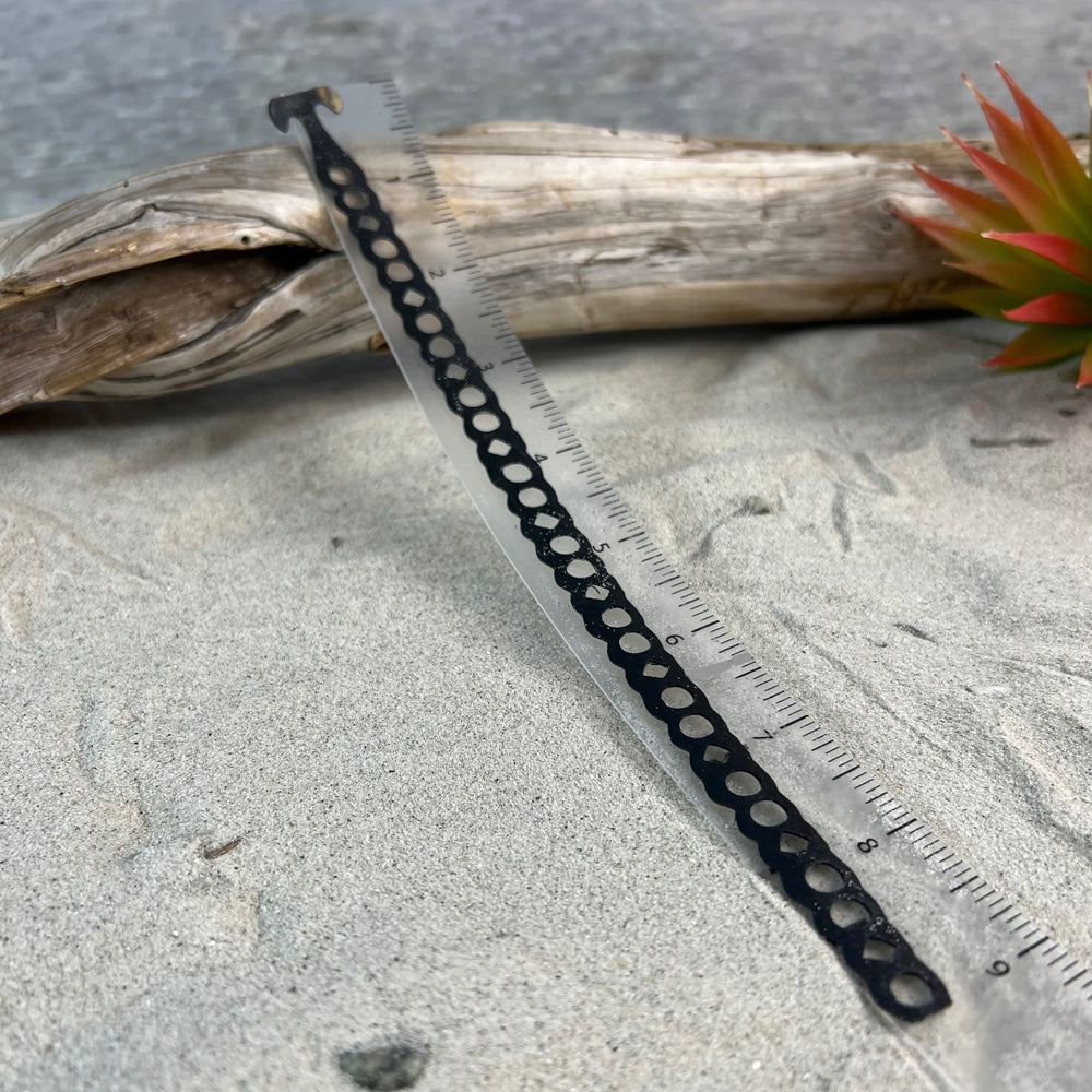 This bracelet extender is .5 wide and 9 inches long. It is a series of holes from top to bottom. It has a t-shaped clasp. This image shows an extender cut to have only four holes. The fourth hole is connected to the t-shape clasp of the bracelet.
