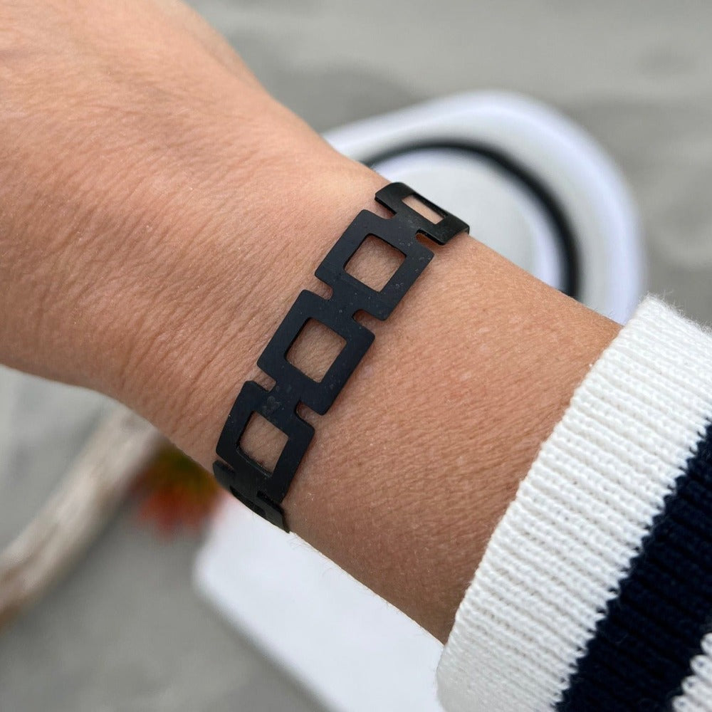 This bracelet was made by cutting intricate designs into a bicycle tube. It looks like a series of rectangle shapes linked together. It has a t-shape clasp that fits into one of six holes making it suitable for a wide range of wrist sizes.